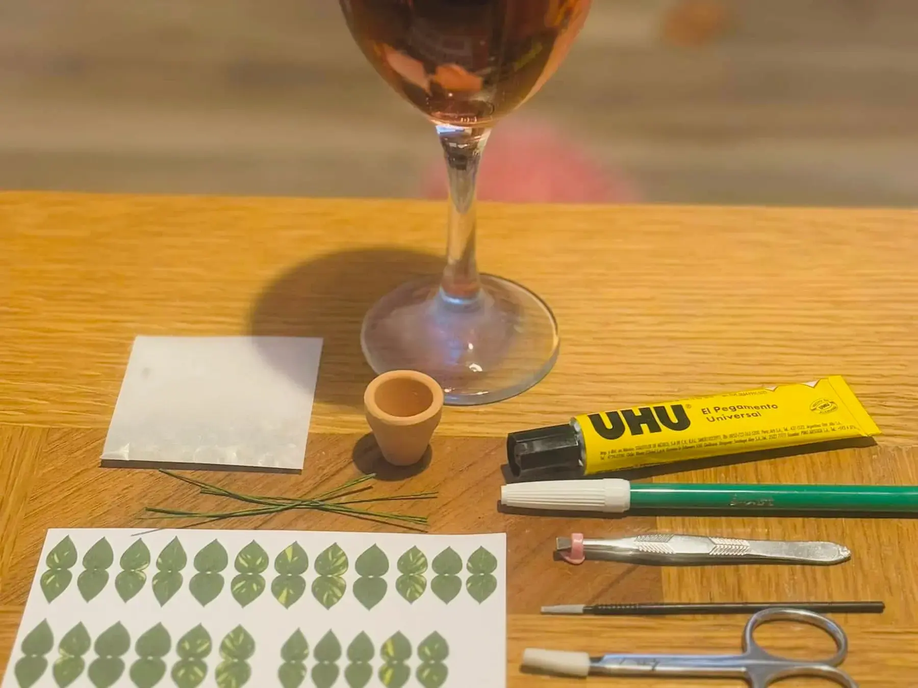 Evening paper plant crafting setup with tools and a glass of wine
