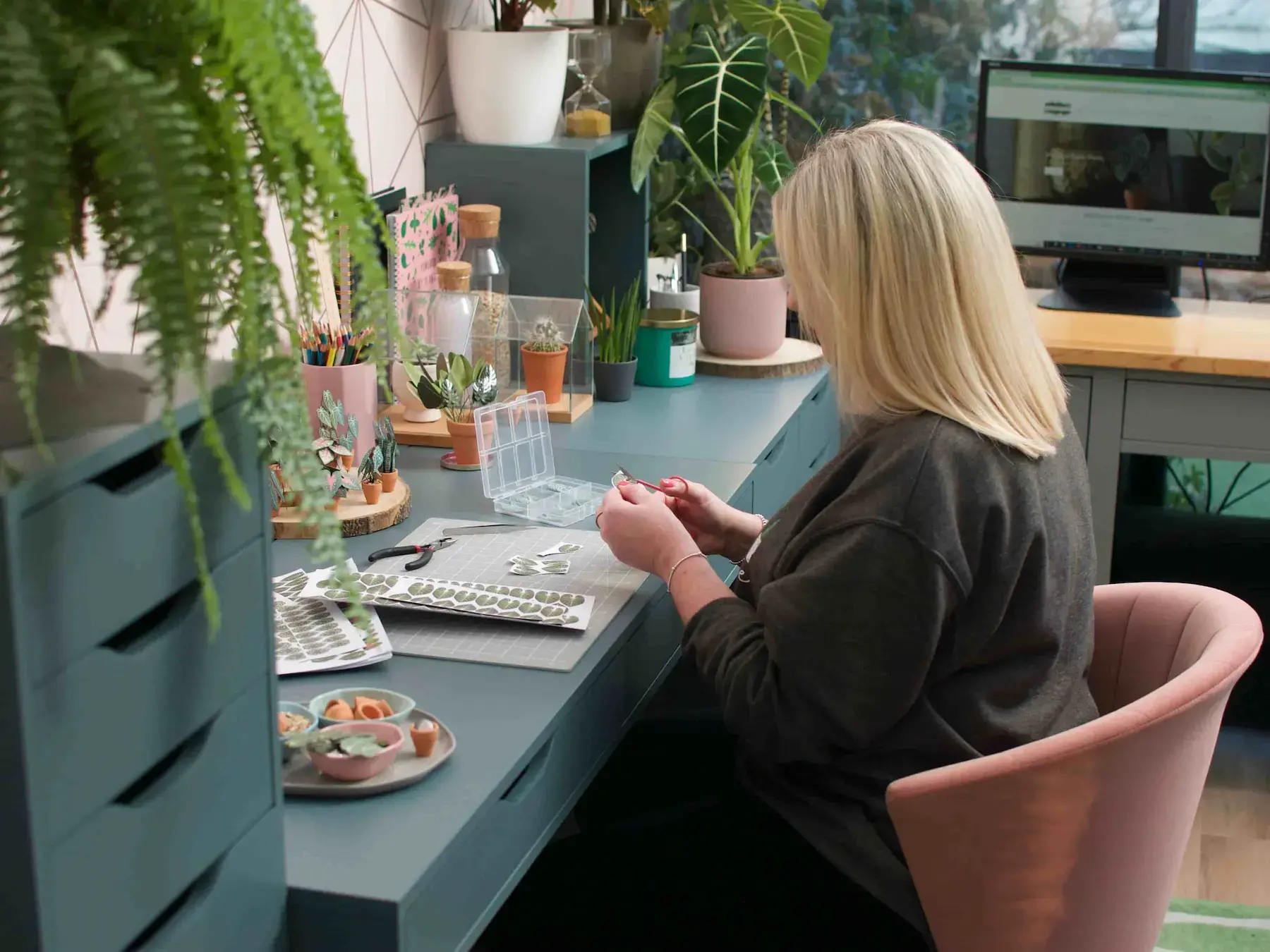 Nicole crafting miniature paper houseplants at her studio desk